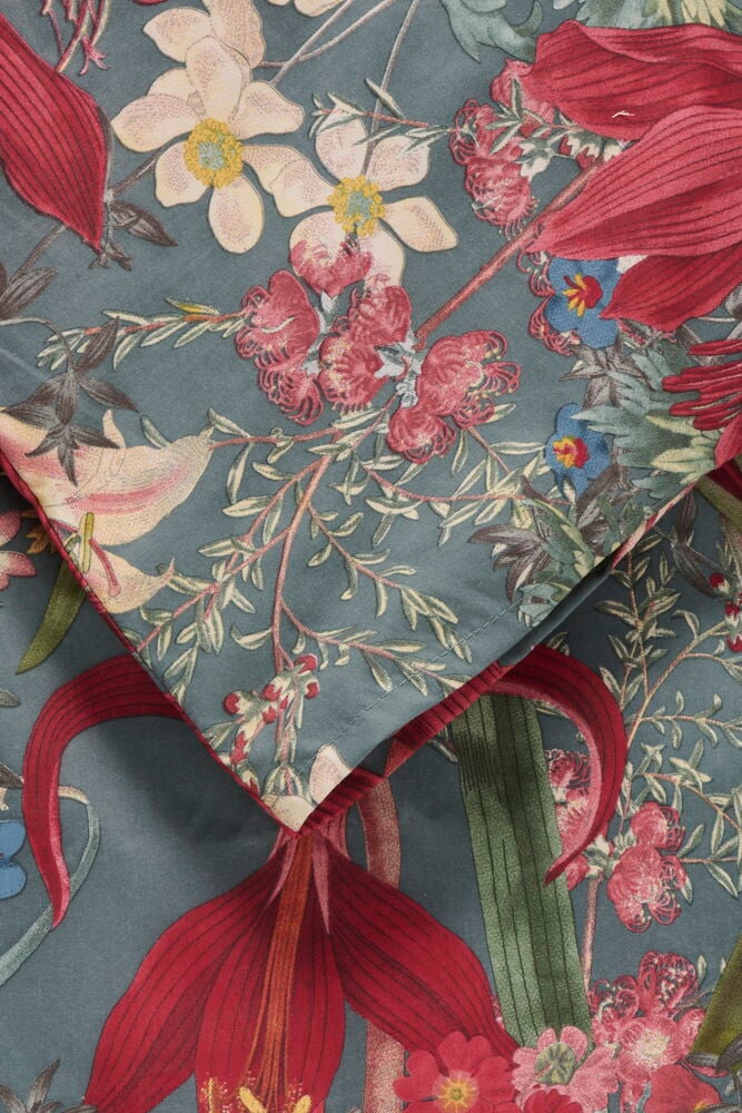 Et Sengesett Micro Noelle Polyester med turkis bakgrunn og rødt, rosa, hvitt, blått blomstermønster, brettet.