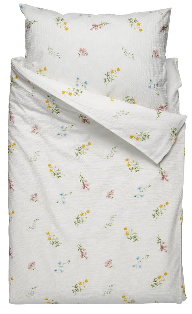 Valkoinen kukallinen pussilakana, jossa on kudottu rakenne.