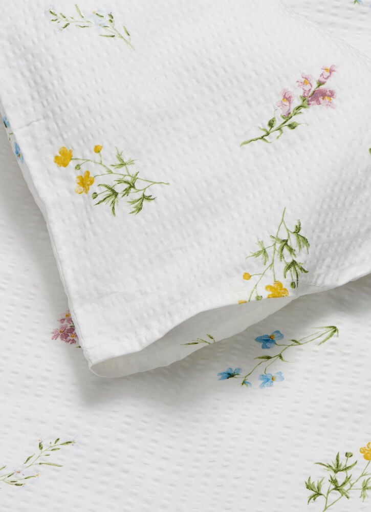 Nahaufnahme eines weißen, strukturierten Bettwäsche-Sets Becky mit kleinen, bunten Blumenmustern auf einem passenden Bettbezug.