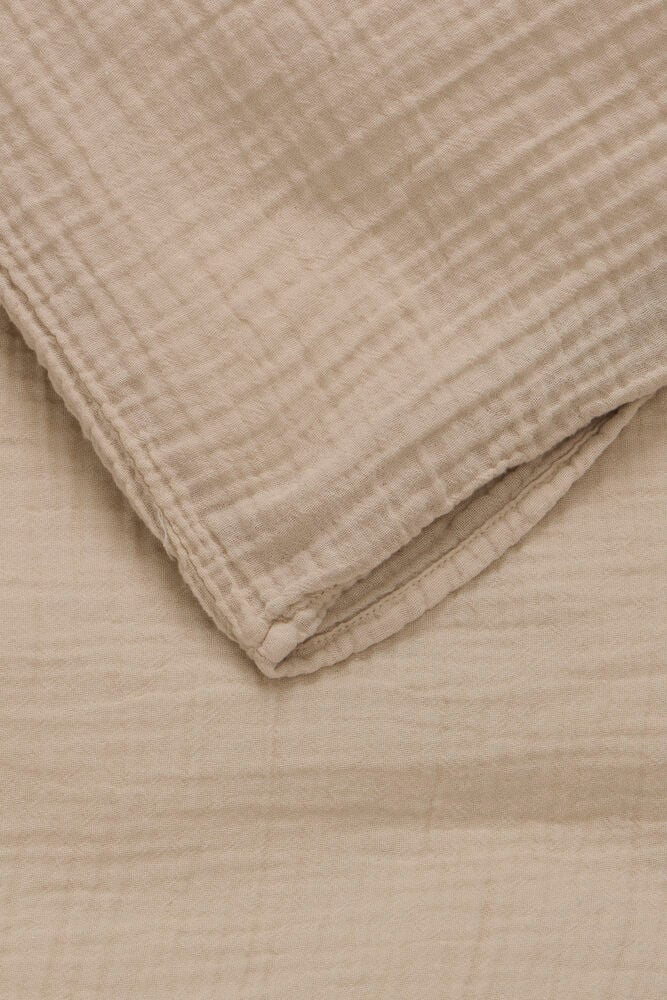 Beige påslakanset i mjuk bomullsmuslin med struktur.