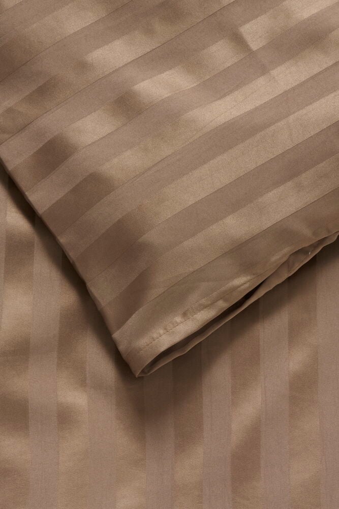 Närbild på ett ljusbrunt påslakanset i satin med vertikala ränder.
