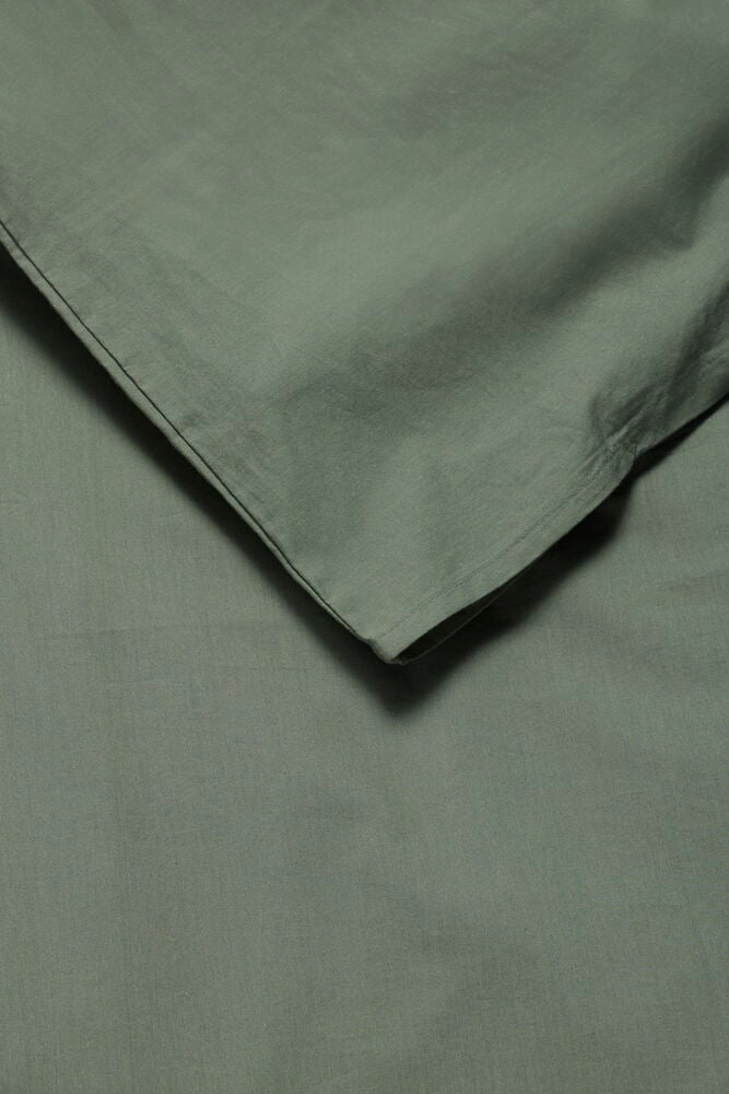 Eine Nahaufnahme eines gefalteten grünen Elsaform Bettwäsche-Sets, das einen Bettbezug und Kissenbezug zeigt.