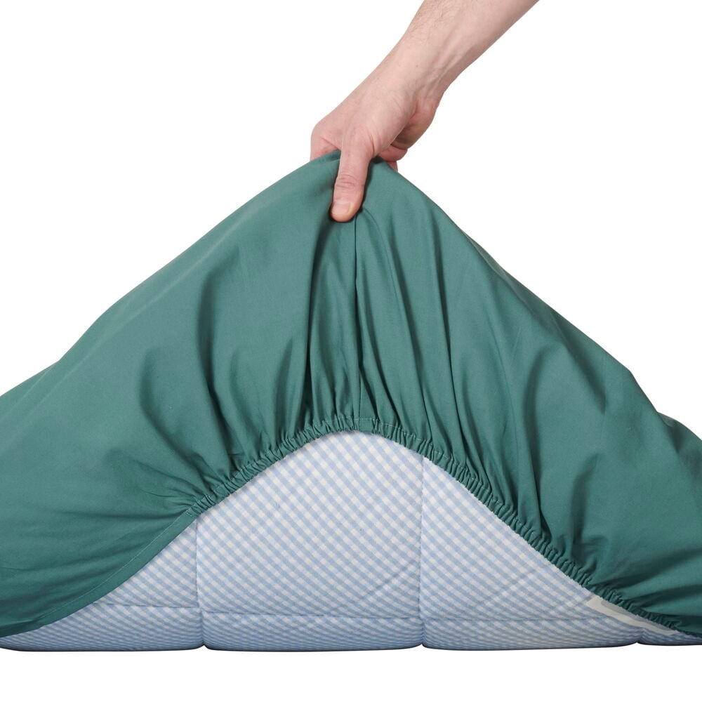 Grönt dra-på-lakan på madrashörn, hand drar upp.