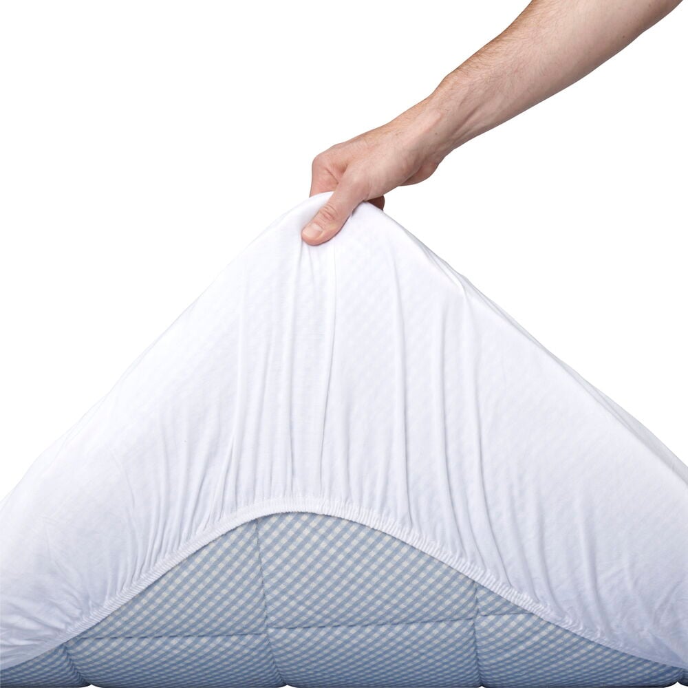 En hand drar på vitt dra-på-lakan på madrass.