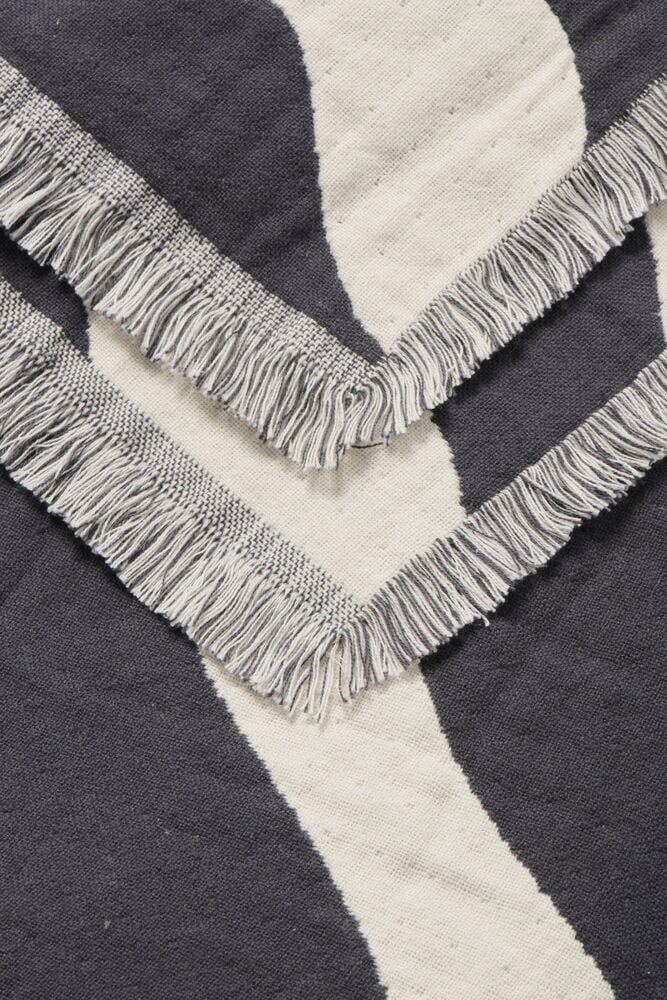 Harmaavalkoinen puuvillapäiväpeitto seeprakuviolla ja hapsuilla.