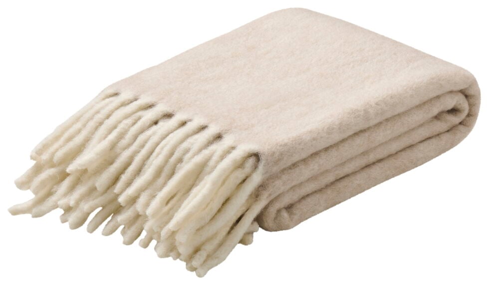 Et vekt beige pledd med dekorative frynser.