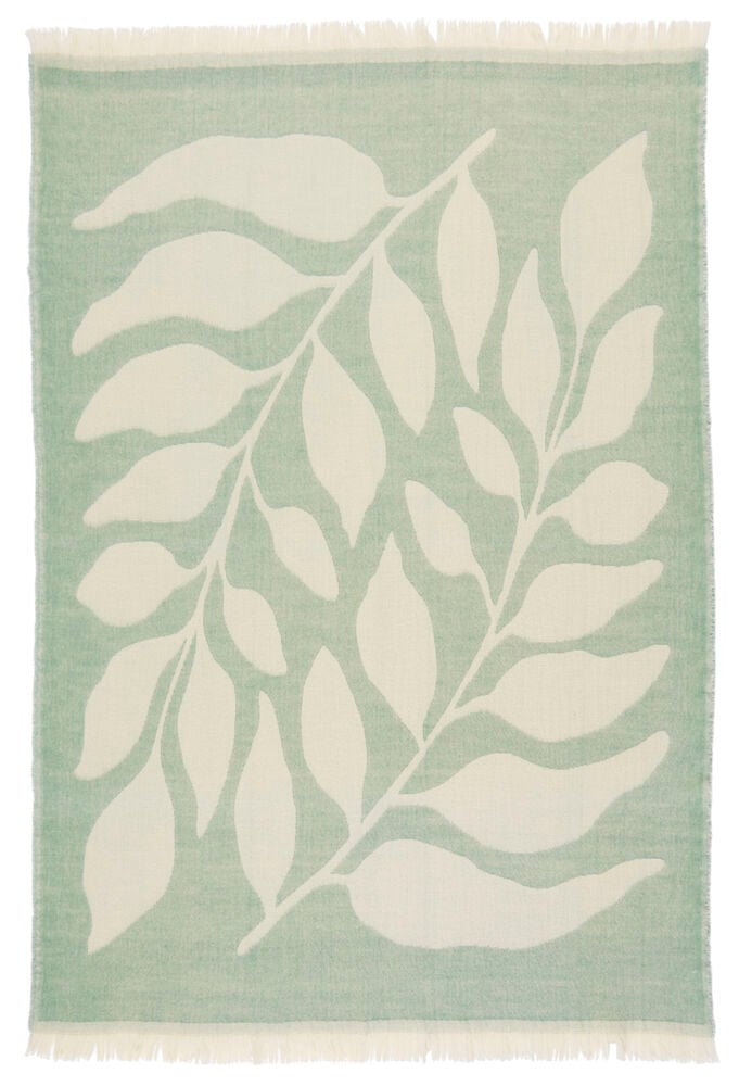 Grön ullpläd med vita blad och fransar.