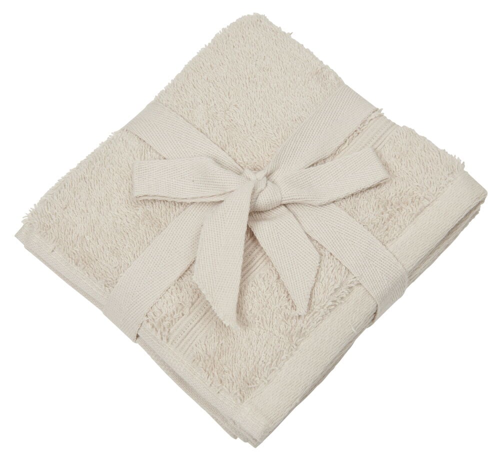 Drei sandfarbene Waschlappen mit einer Schleife zusammengebunden.