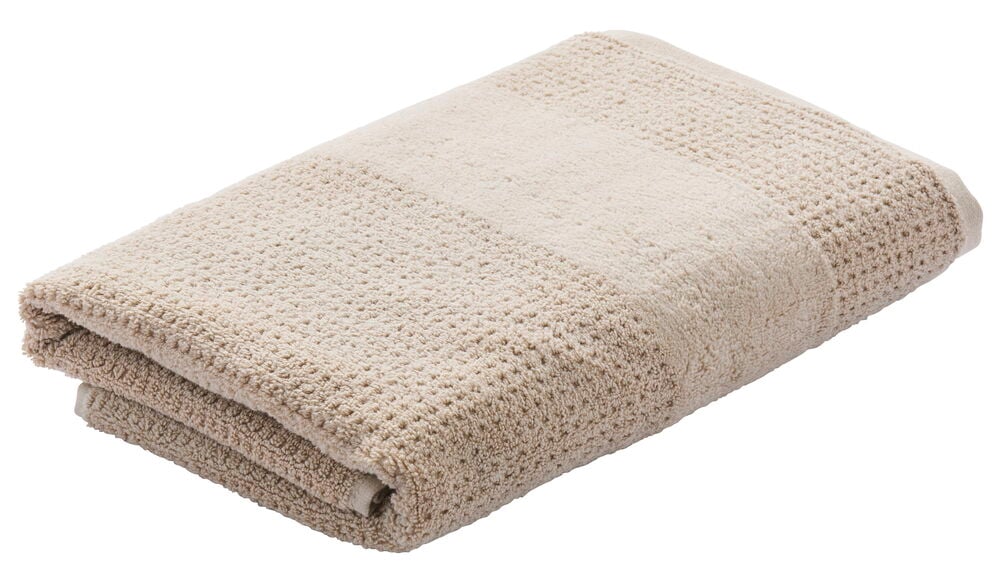 Beige painotettu kylpypyyhe, jossa on kudottu rakenne.