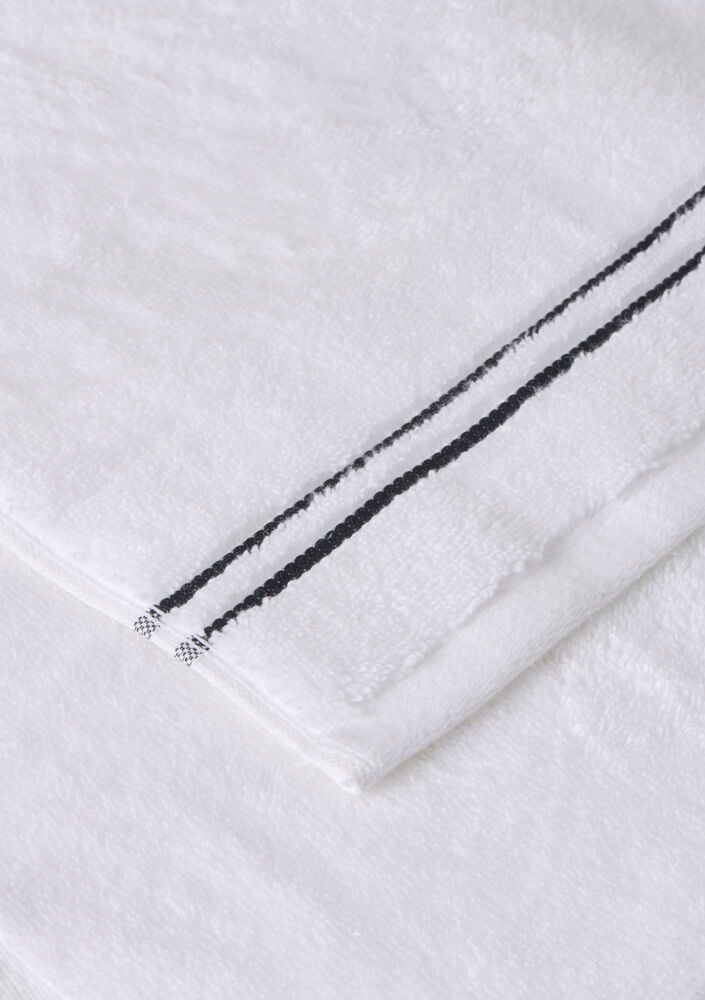 Vikta vita tvättlappar med svarta dekorativa ränder.