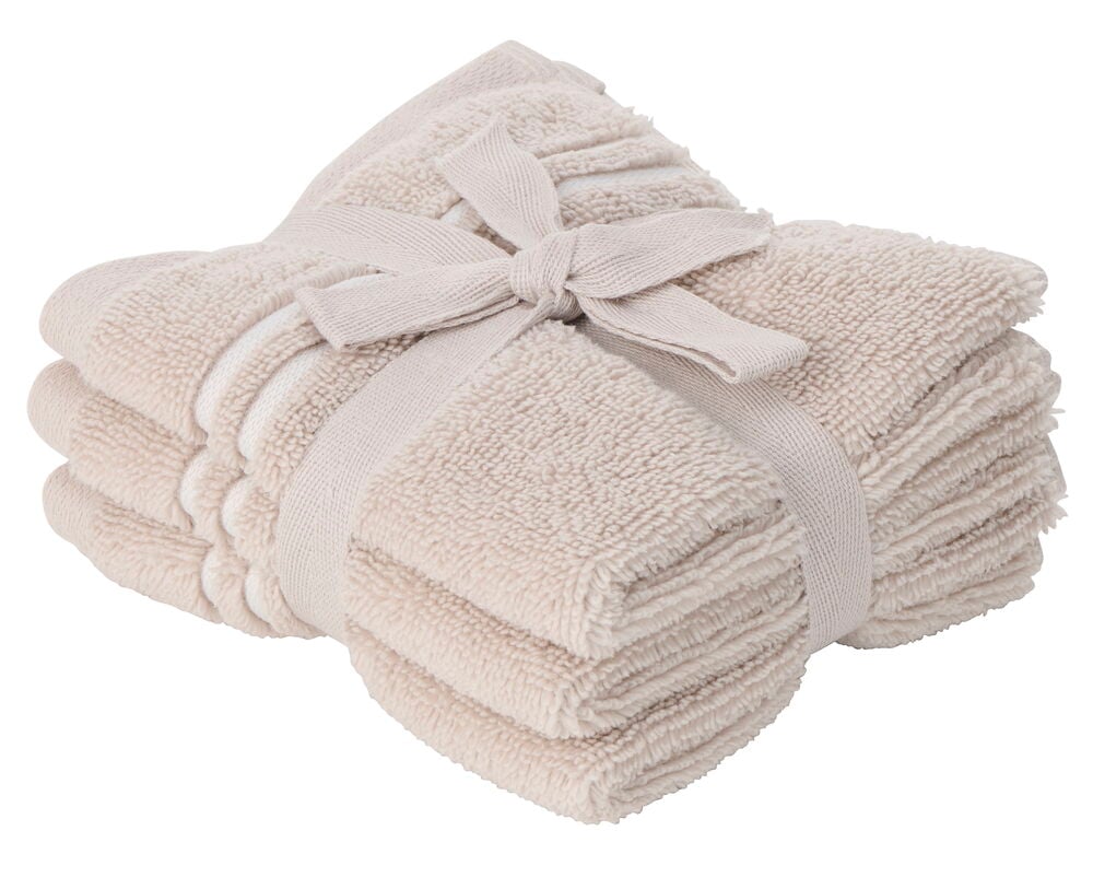 En Hotel Collection 3-pakke med beige vaskekluter i bomull, pent stablet og bundet med et bånd.