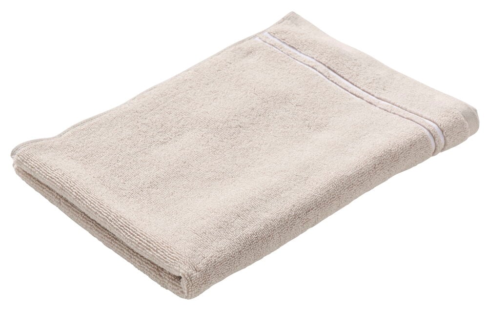 Et sammenbrettet beige bomullshåndkle med to hvite striper nær den ene enden.