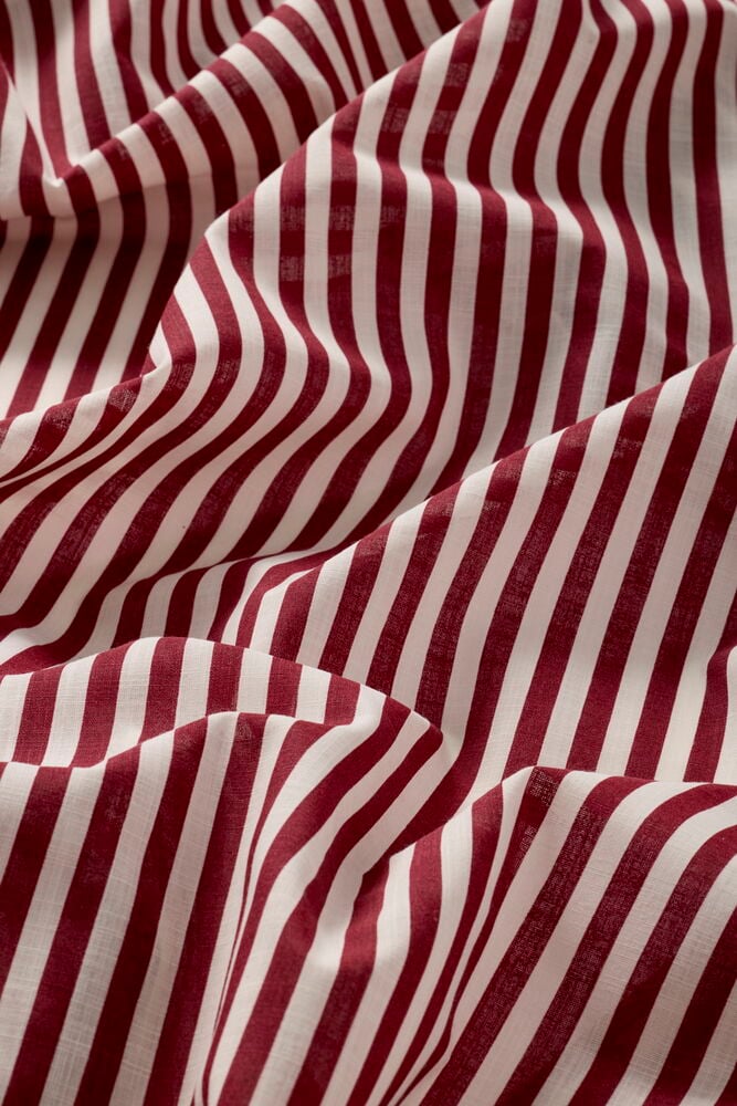 Røde og hvite stripete polyester gardinlengder Sundborn, nærbilde med draperte folder.