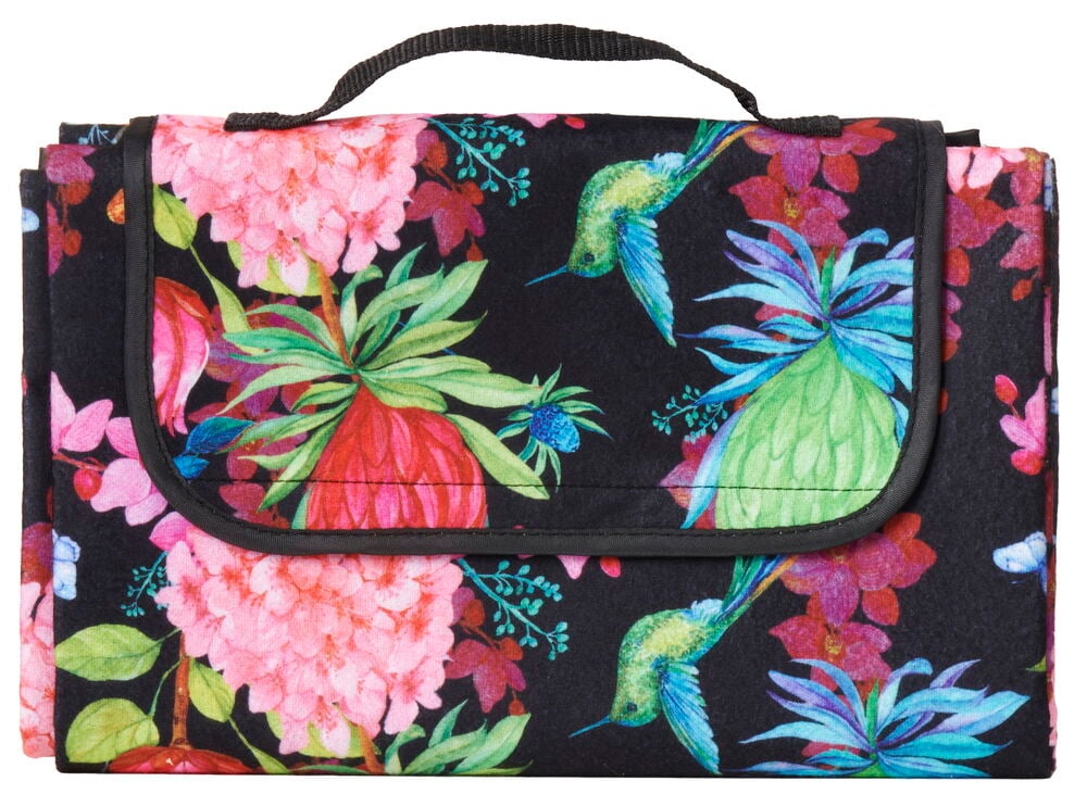 Sammenleggbar piknikteppe med tropisk mønster og håndtak.