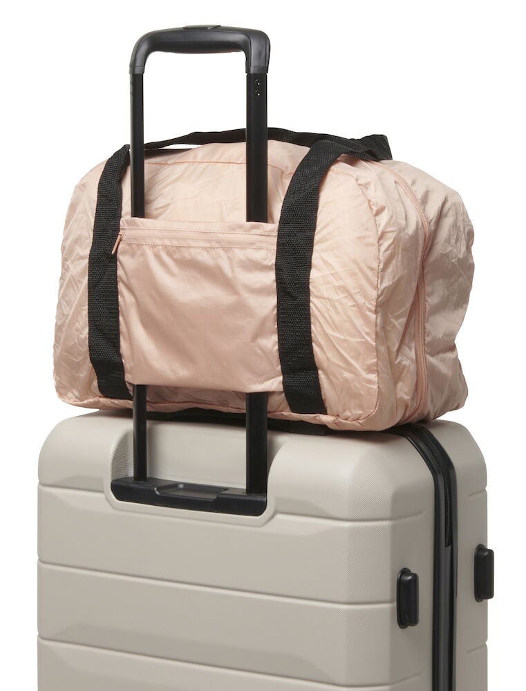 En rosa duffelbag på en beige resväska.