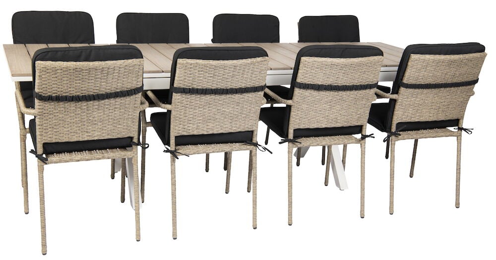 Svarta sittdynor på rottingstolar runt trädgårdsbord.