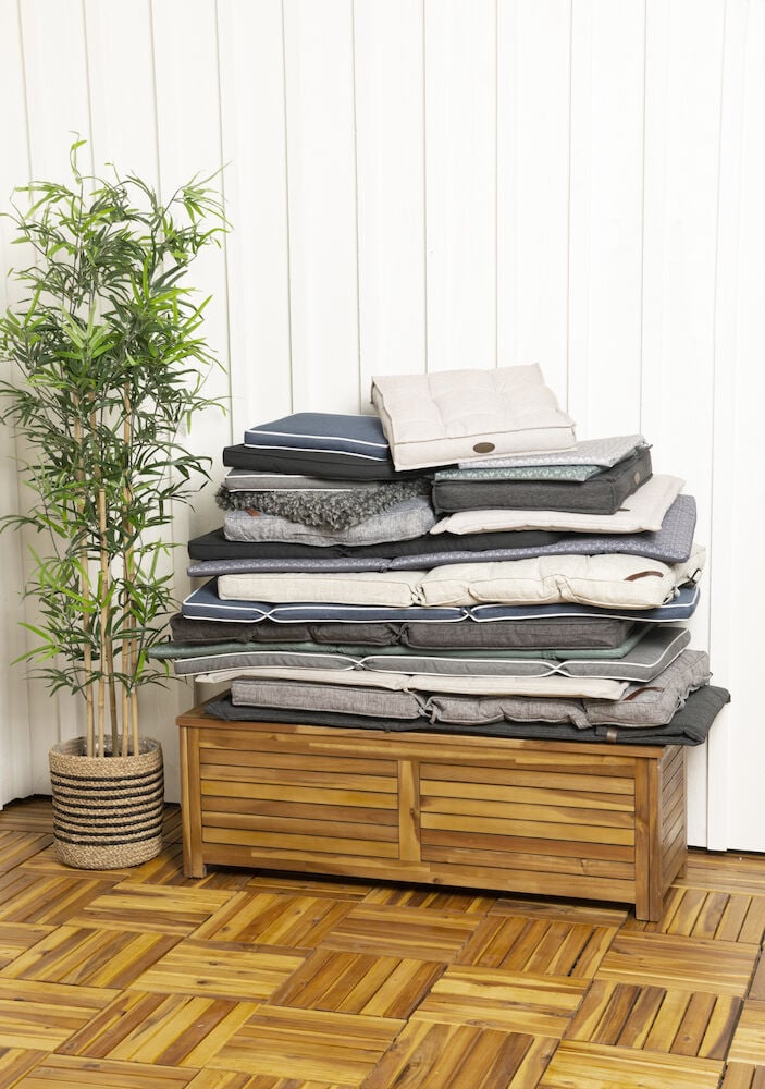 En hög ryggdyna melerad grå på träbänk.