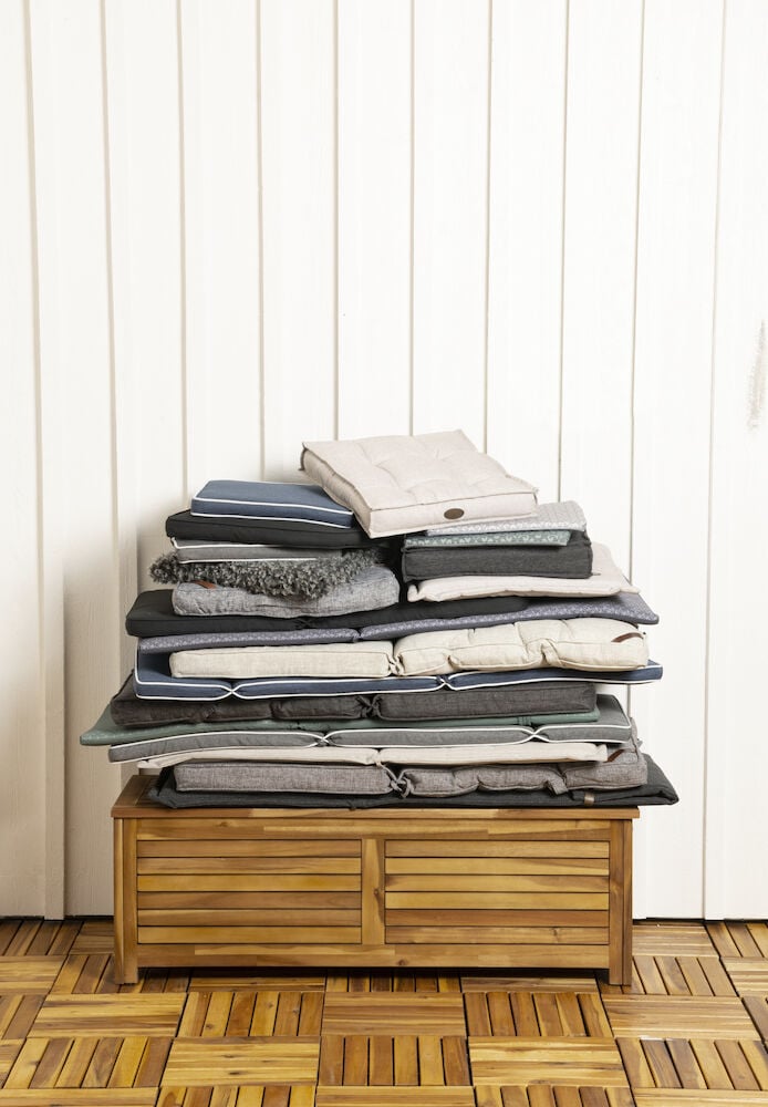 En hög med sittdynor på trälåda inomhus.