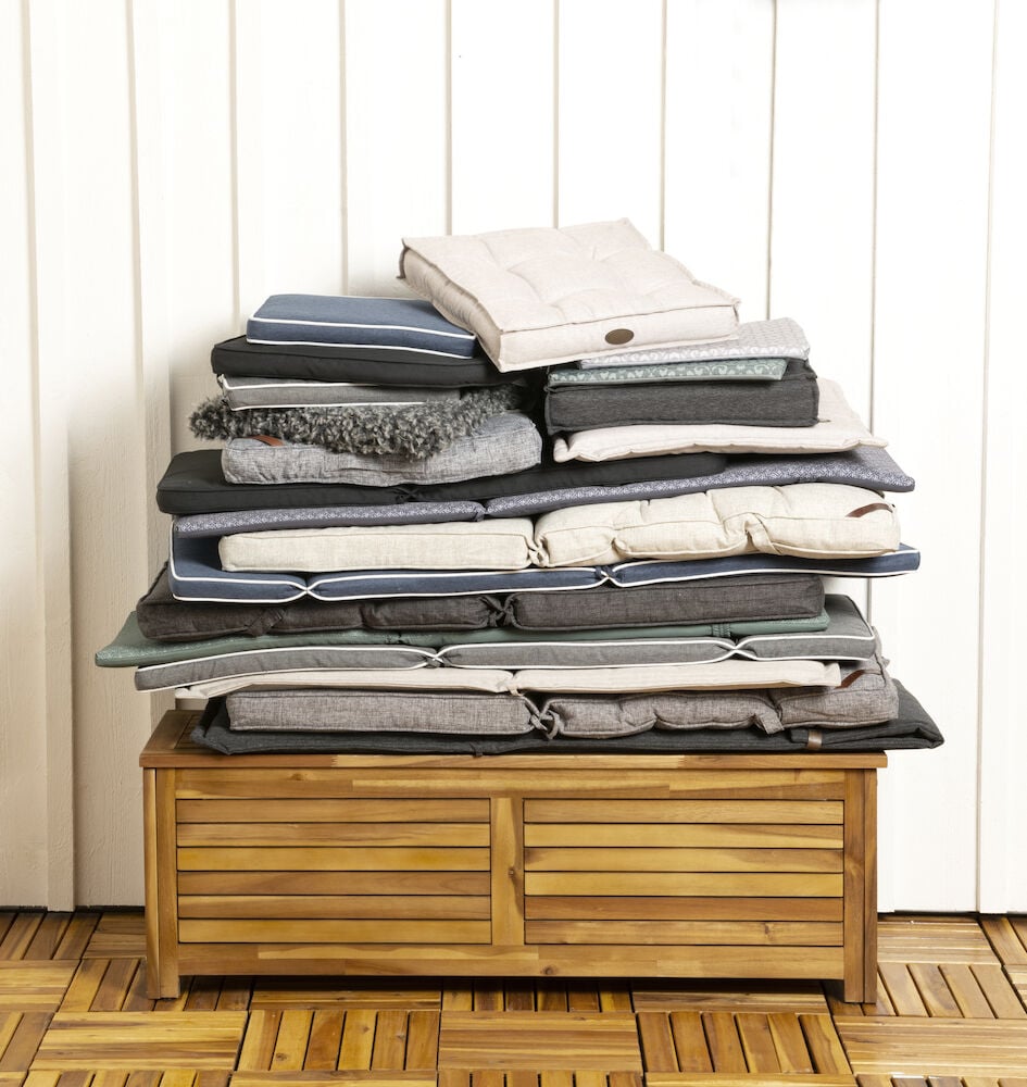 En hög med sittdynor på en trälåda.