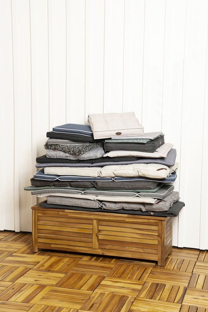 En stapel dynor på en träförvaringslåda.