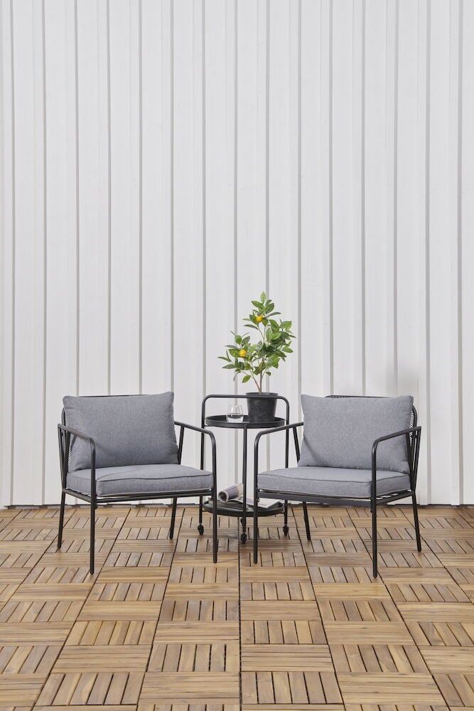 Kaksi harmaata ulkotuolituolia tyynyillä ja pyöreä pöytä.