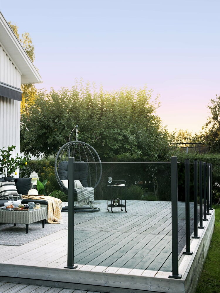 Rökfärgat glasräcke monterat på träterrass utomhus.