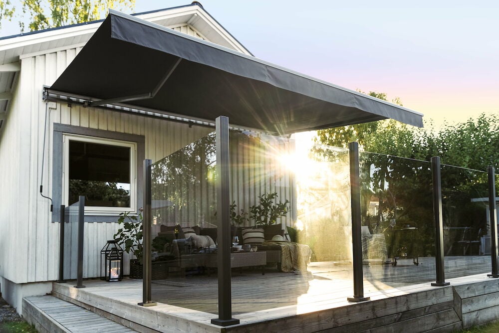 Rökgrått glasräcke monterat på en solig träaltan.