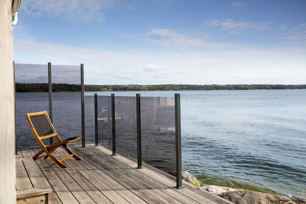 Rauchgraues Glasgeländer auf der Terrasse am See.