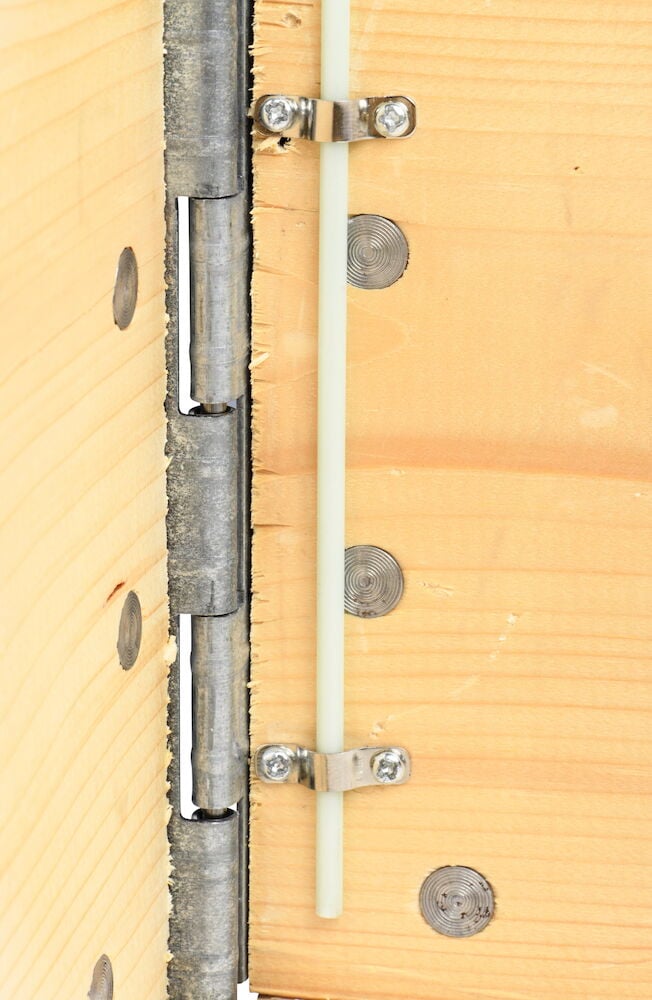 Metallscharniere und Kunststoffhalterung auf Holzoberfläche Nahaufnahme.