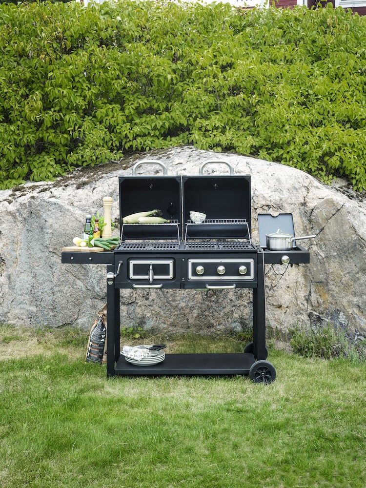 Svart kombigrill med två lock och sidobord utomhus.