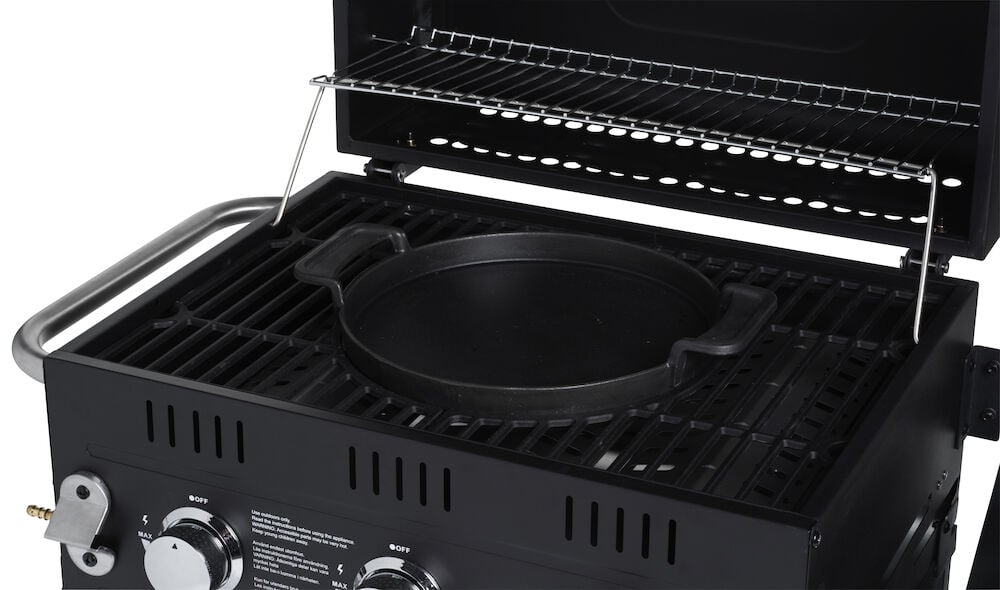 Svart støpejernswokpanne plassert i gassgrill.