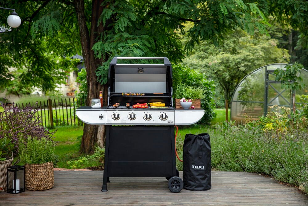 Weißer und schwarzer Propangasgrill Evolution GS 4 Brenner, mit Grillgut und einer schwarzen BBQ-Abdecktasche.
