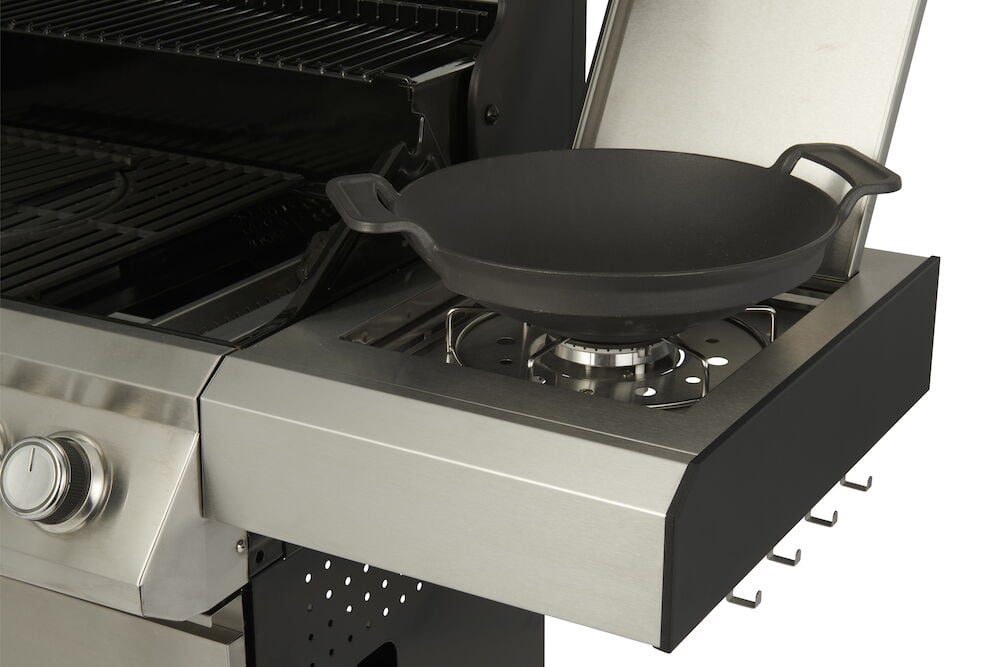 Gasolgrill med sidobrännare och gjutjärnspanna.