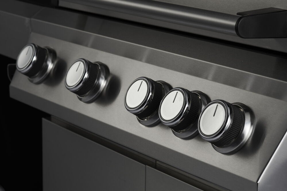 Gasolgrill med fem kontrollvred i metall.