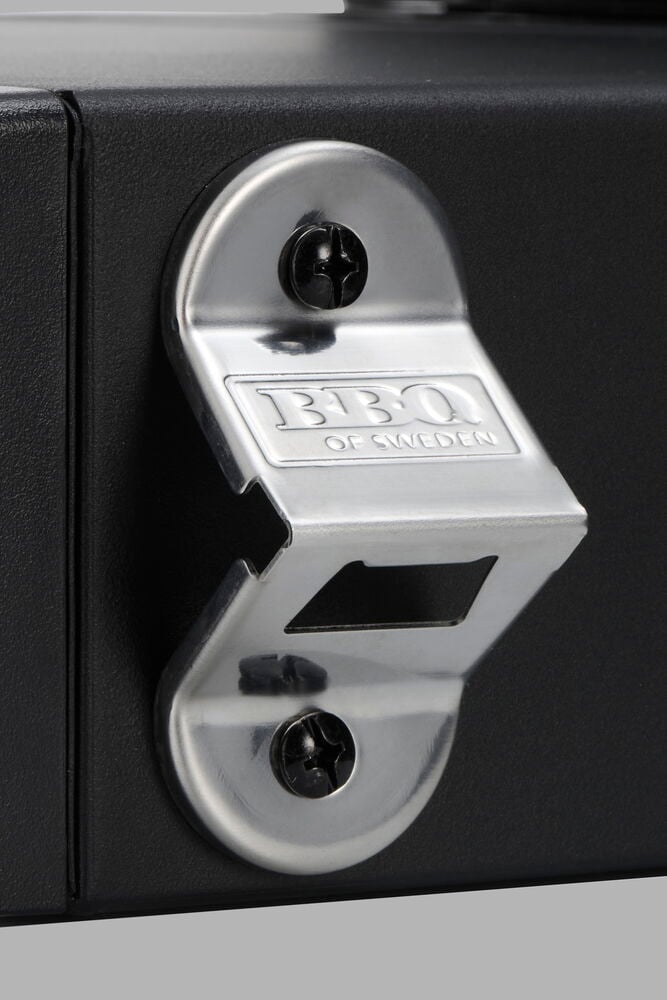 Silberner Metallflaschenöffner an einem schwarzen Propangasgrill Titan montiert.