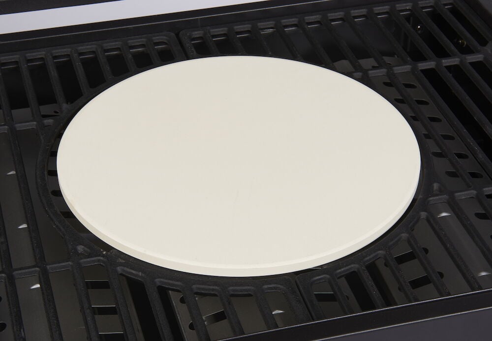 Rund pizzastein i keramikk plassert på en grill.