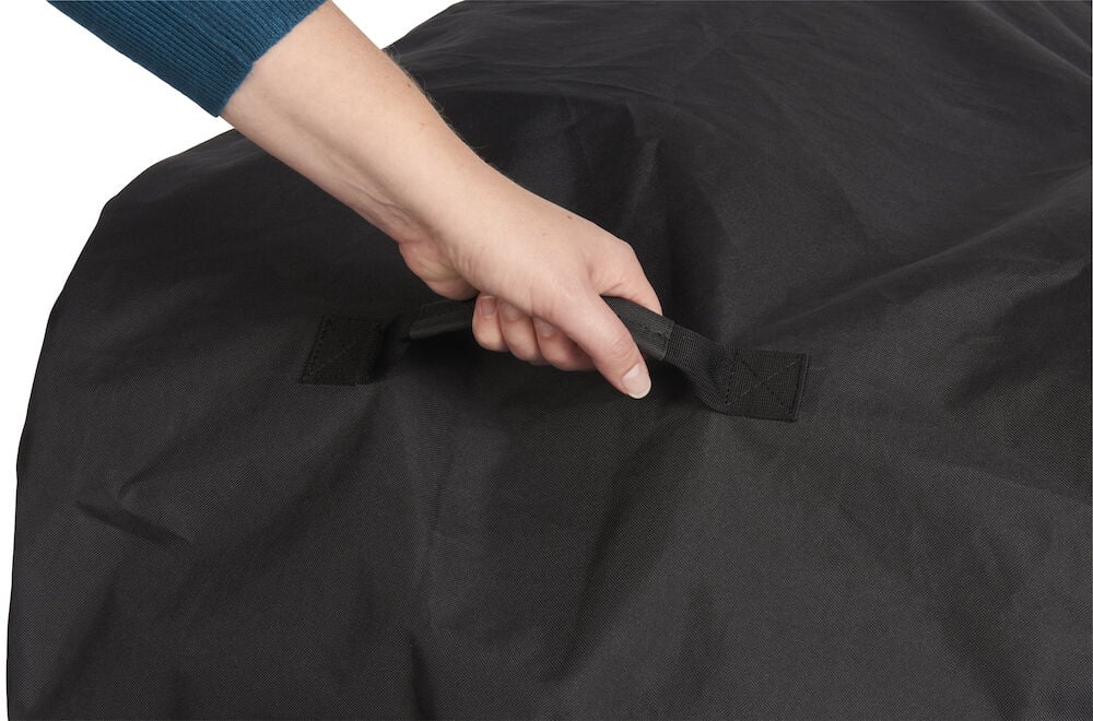 Hand placerad på svart grillöverdrag med handtag.