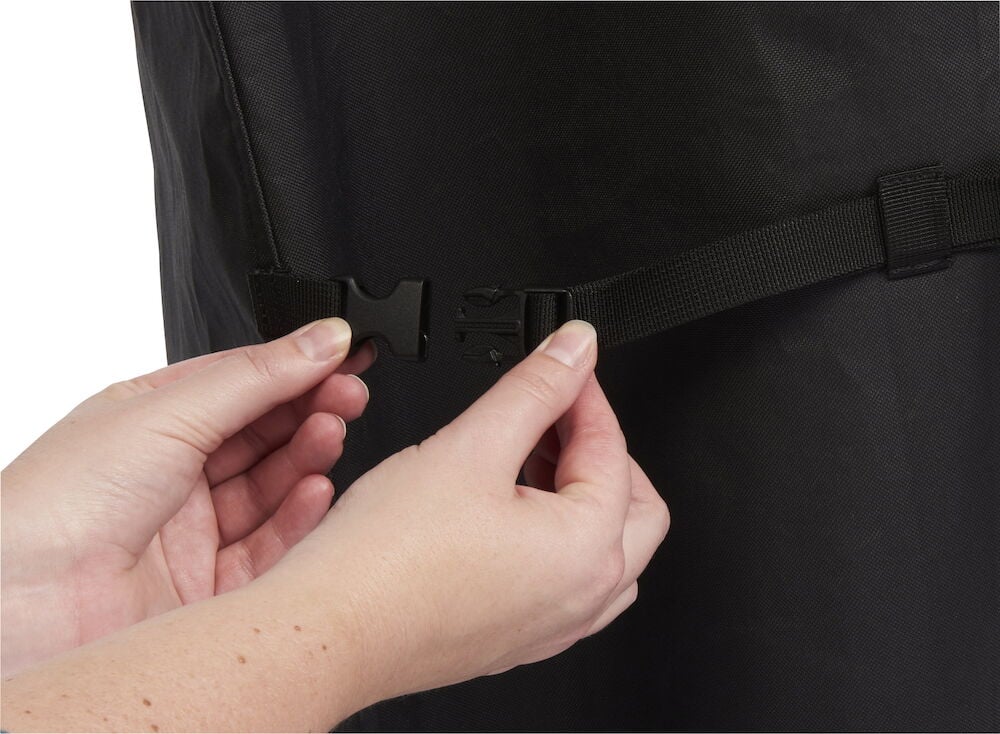 Hand knäpper spänne på svart grillöverdrag.