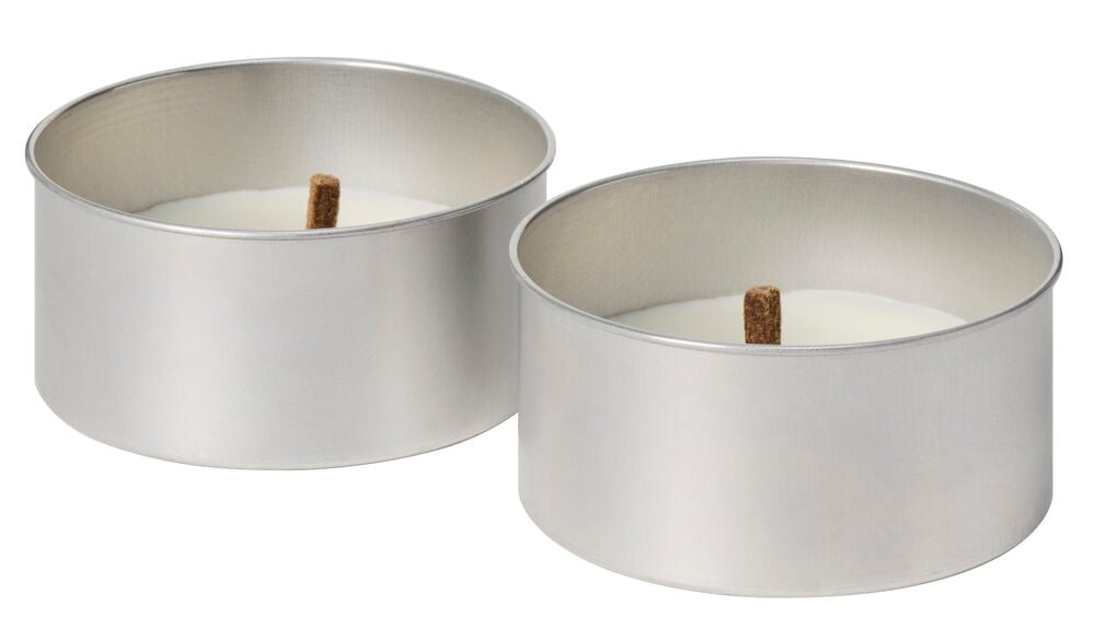 Två stora vita värmeljus i metallkoppar.