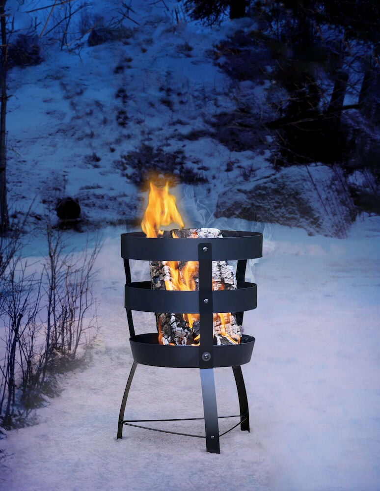 Svart eldkorg med ved och eld utomhus vintertid.