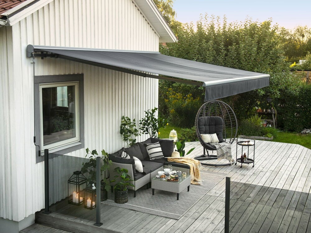 Grå motoriserad terrassmarkis monterad ovanför uteplats.