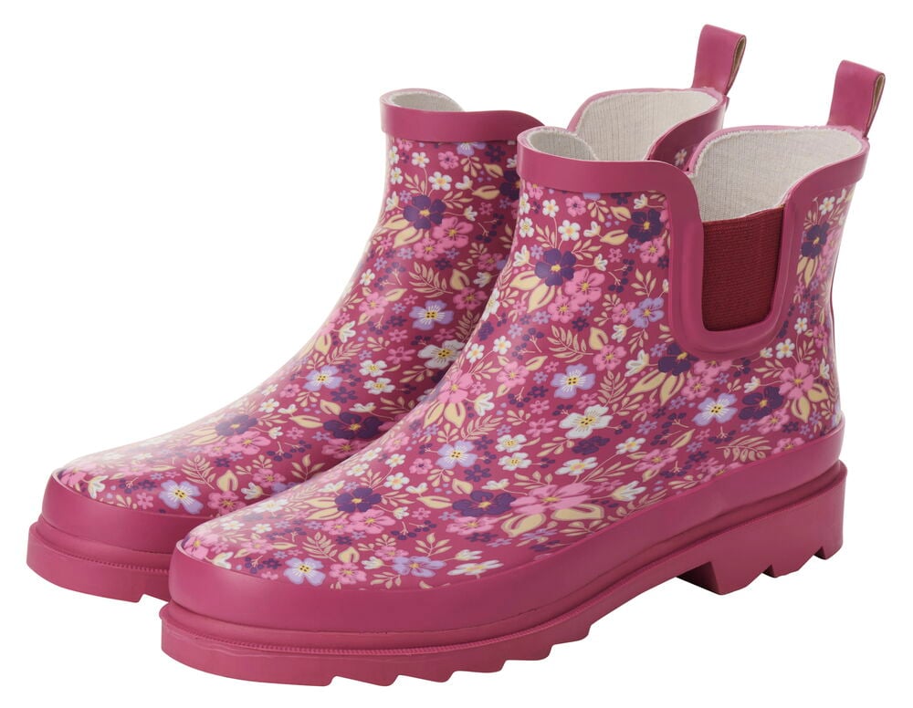 Vaaleanpunaiset matalat kumisaappaat kukkakuviolla.