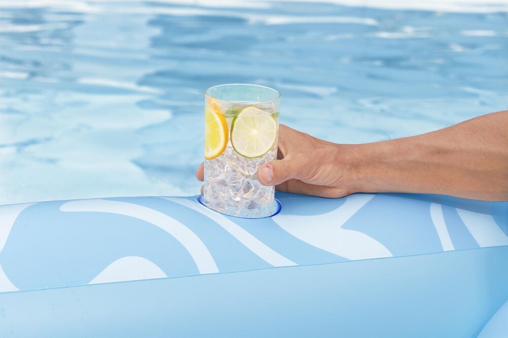 Hand på blå uppblåsbar solsäng med dryckeshållare.