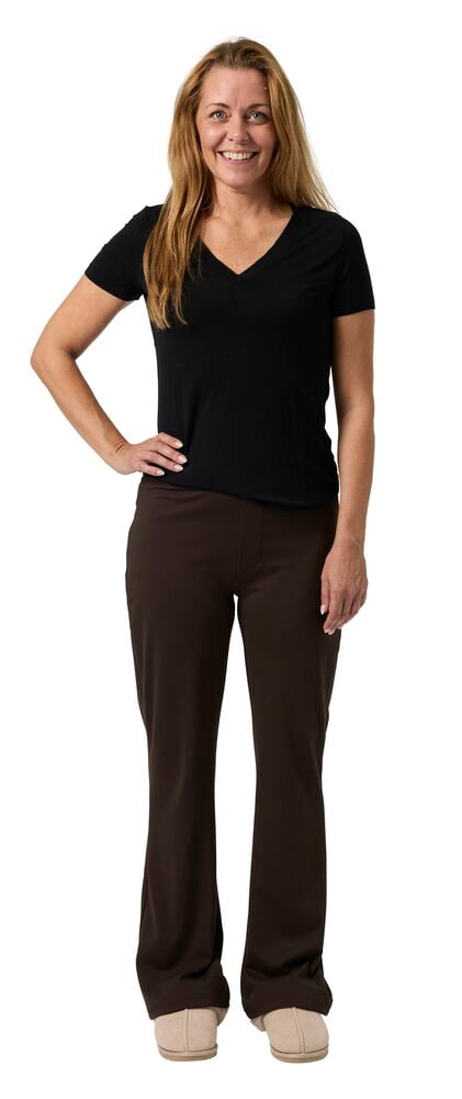 Kvinne iført brune bootcut-bukser, en svart v-hals t-skjorte og lysebeige sko.