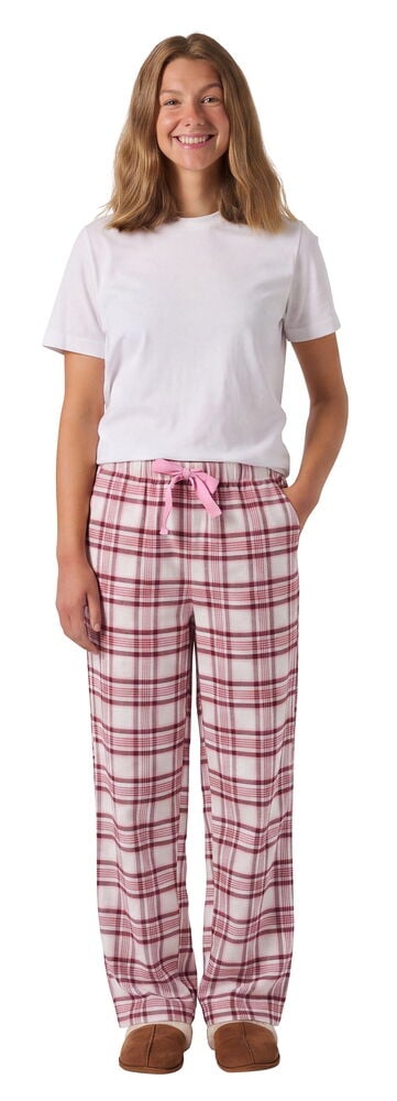 Kvinna i rosa- och vitrutiga flanellbyxor med rosa rosett, en vit t-shirt och bruna tofflor.