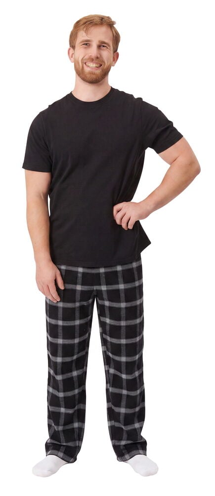 Mann in schwarz-weiß karierter Flanellhose, schwarzem T-Shirt und weißen Socken.