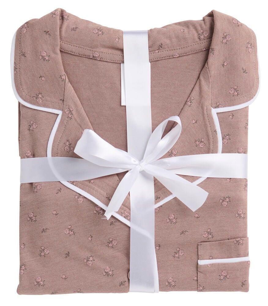 Taitettu Pyjama Klara vaaleanpunaisessa kukka-kuviossa valkoisella tereellä ja valkoisella nauhalla.