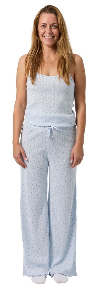 Kvinna bär ett ljusblått Pyjamas Polly set med prickigt mönster, bestående av ett linne och vida byxor.