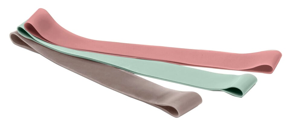 Mini-Widerstandsbänder in Rosa, Mintgrün und Taupe, liegend auf weißem Hintergrund.