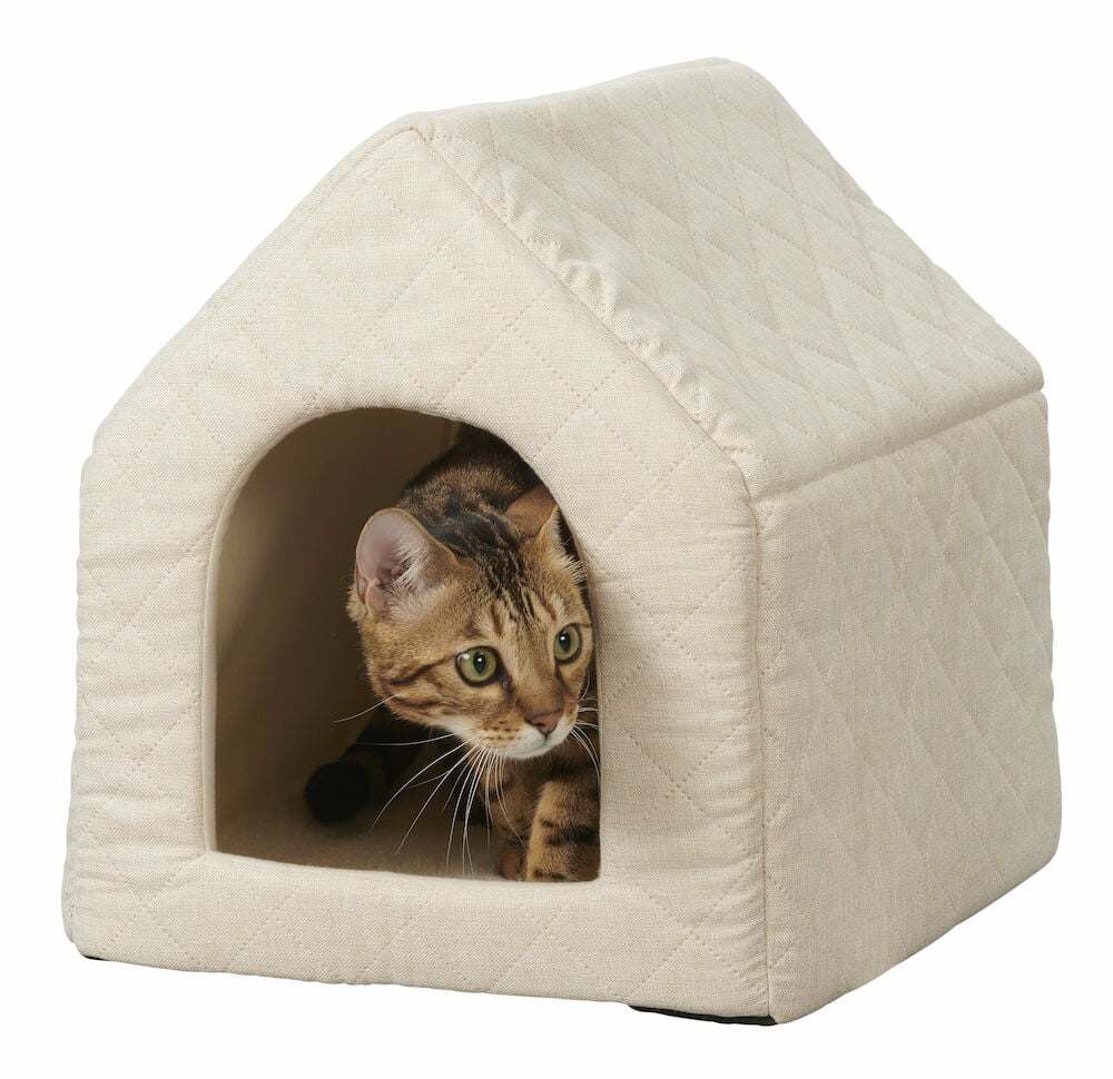 Beige vadderad kattkoja med katt inuti.